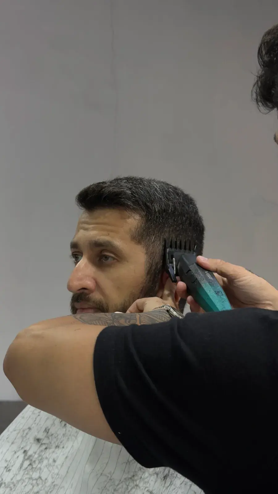 Barbeiro fazendo o degradê na lateral com máquina